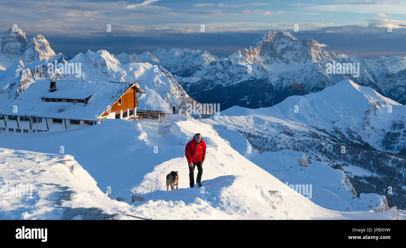 Hiker with german shepherd on the snowy crest surrounded by the high peak of Monte Civetta Dolomites Belluno province Veneto Italy Europe Stock Photo