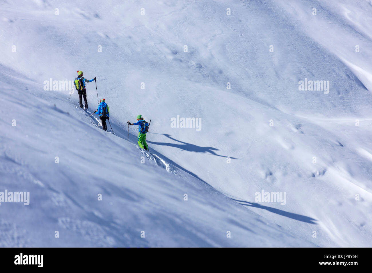 Alpine skiers proceed at high altitude on a sunny day in the snowy landscape Stelvio Pass Valtellina Lombardy Italy Europe Stock Photo