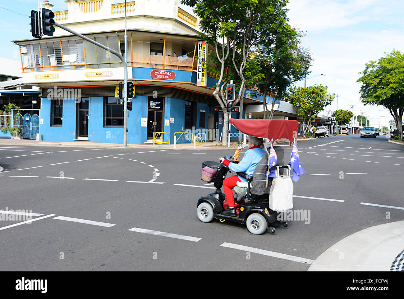 Elderly woman crossing the street in a mobility scooter, Australia Stock Photo