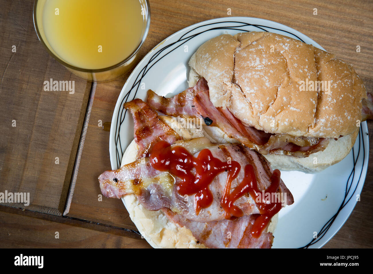 British griddled bacon in a bread roll with ketchup Stock Photo Alamy