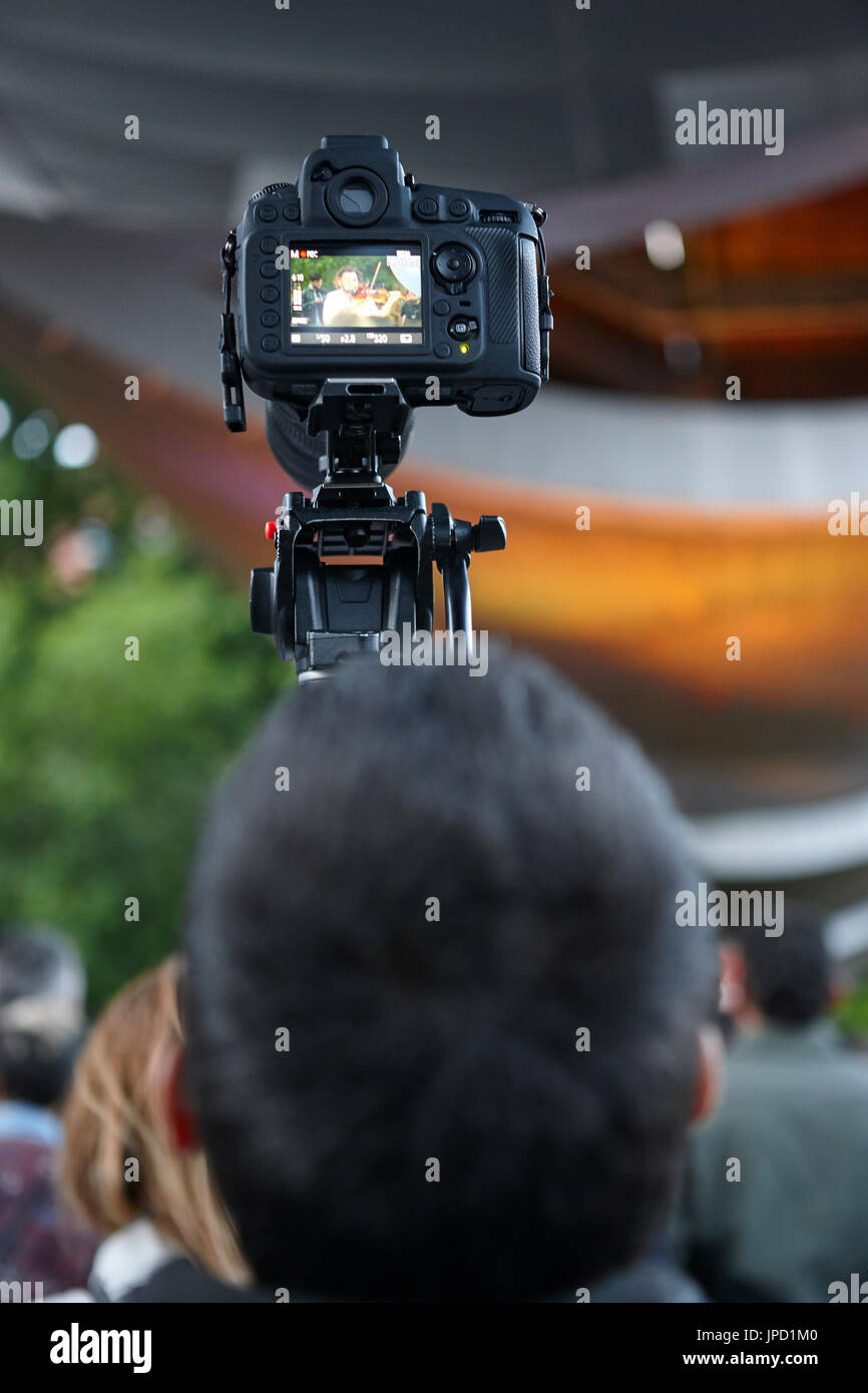 Young man taking photos with a tripod. Outdoors. Vertical Stock Photo