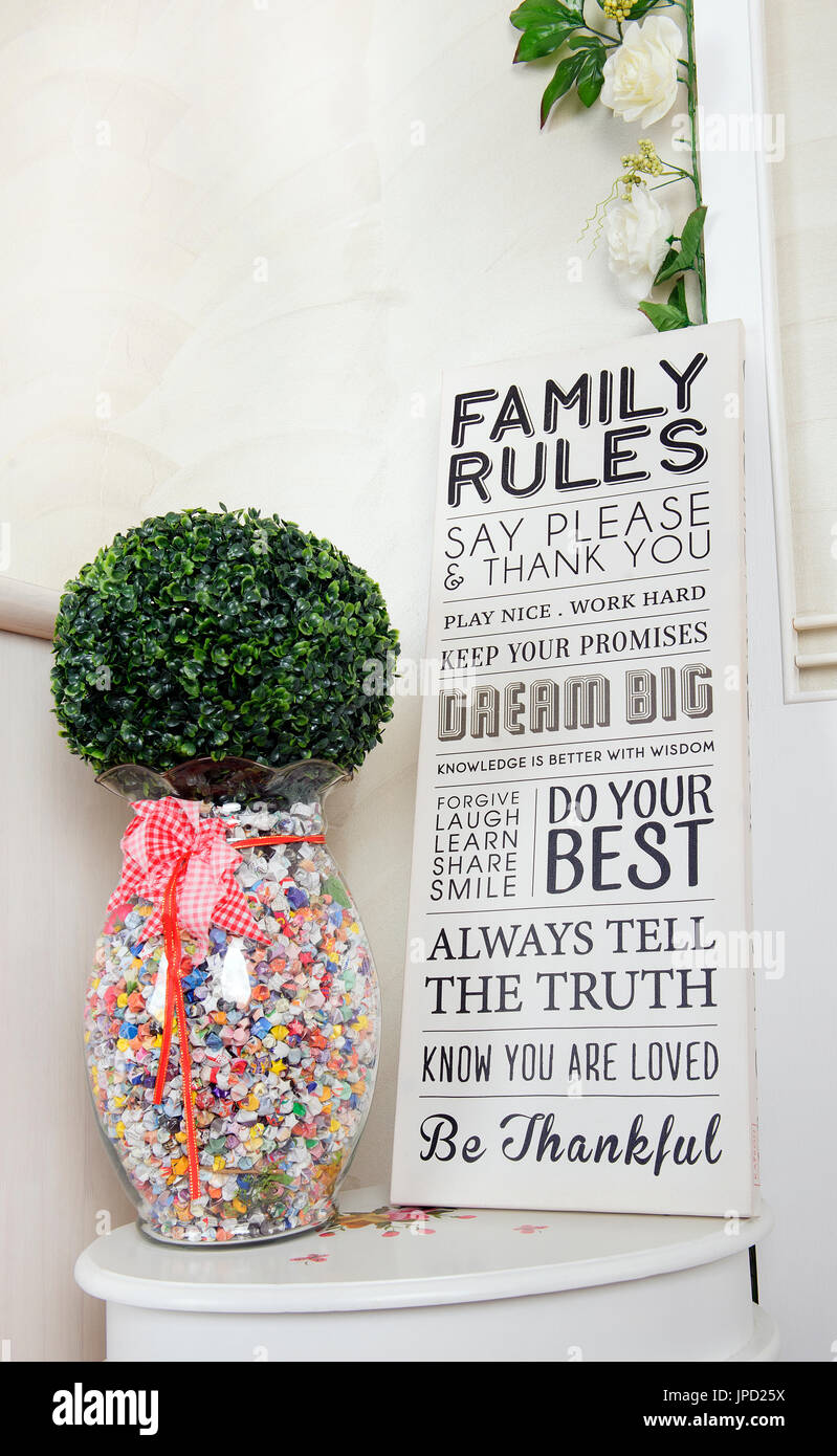 a family rules sign board which writing many meaningful positive words with a glasses jar of handmade paper colorful star and artificial grass Stock Photo