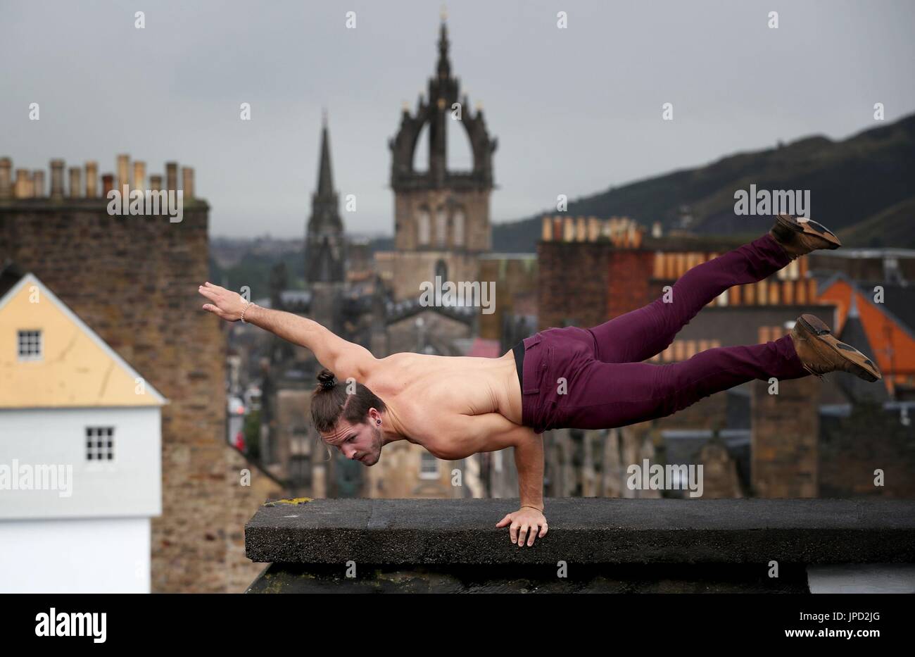 Cal Harris, a member of Head First Acrobats, balances on the roof of Camera Obscura and World of Illusions in Edinburgh, ahead of his Fringe Festival show Elixir. Stock Photo