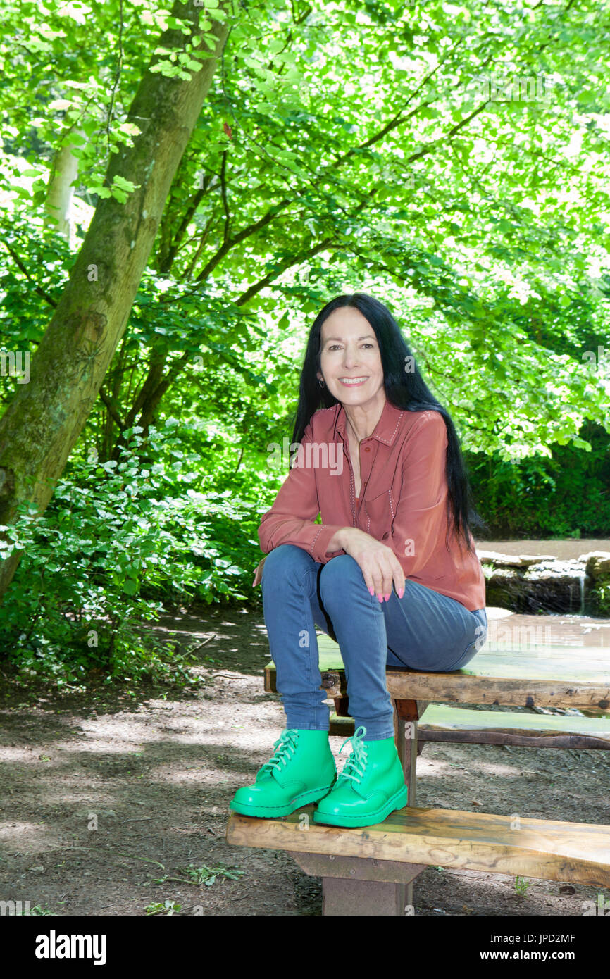 Woman sitting on picnic table in woodland Stock Photo