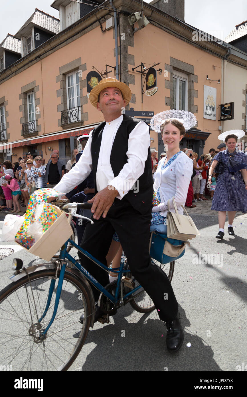 A french couple riding a bicycle in a parade, the Fete des Brodeuses