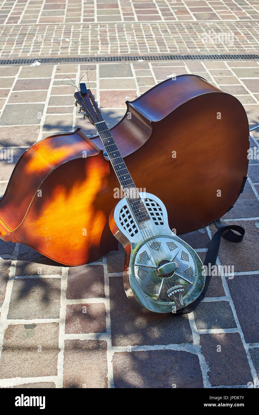 Metallic resonator acoustic guitar leaning on a cello. Also known as National. Stock Photo