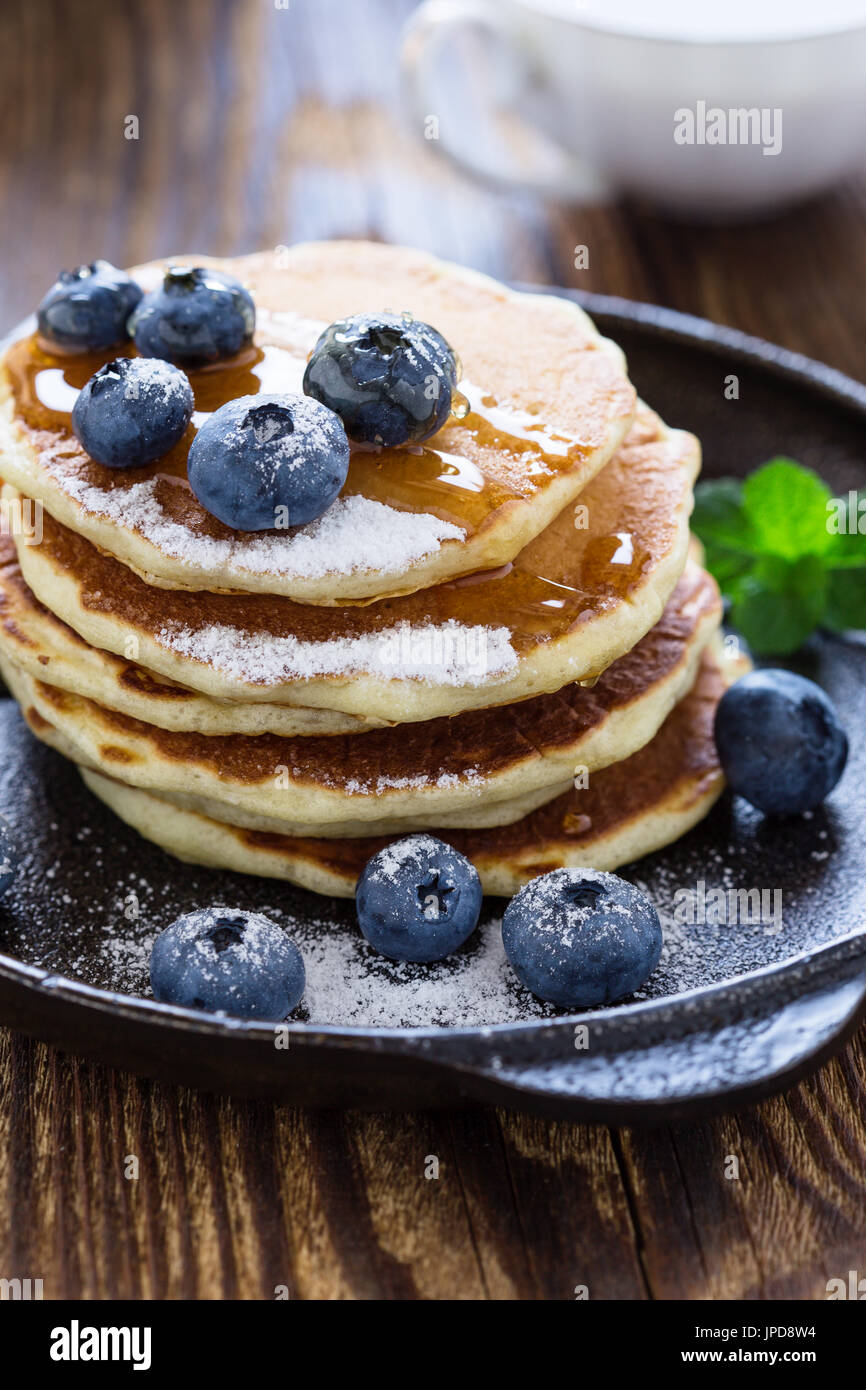 Blueberry buttermilk pancakes in cast iron pan served hot with maple