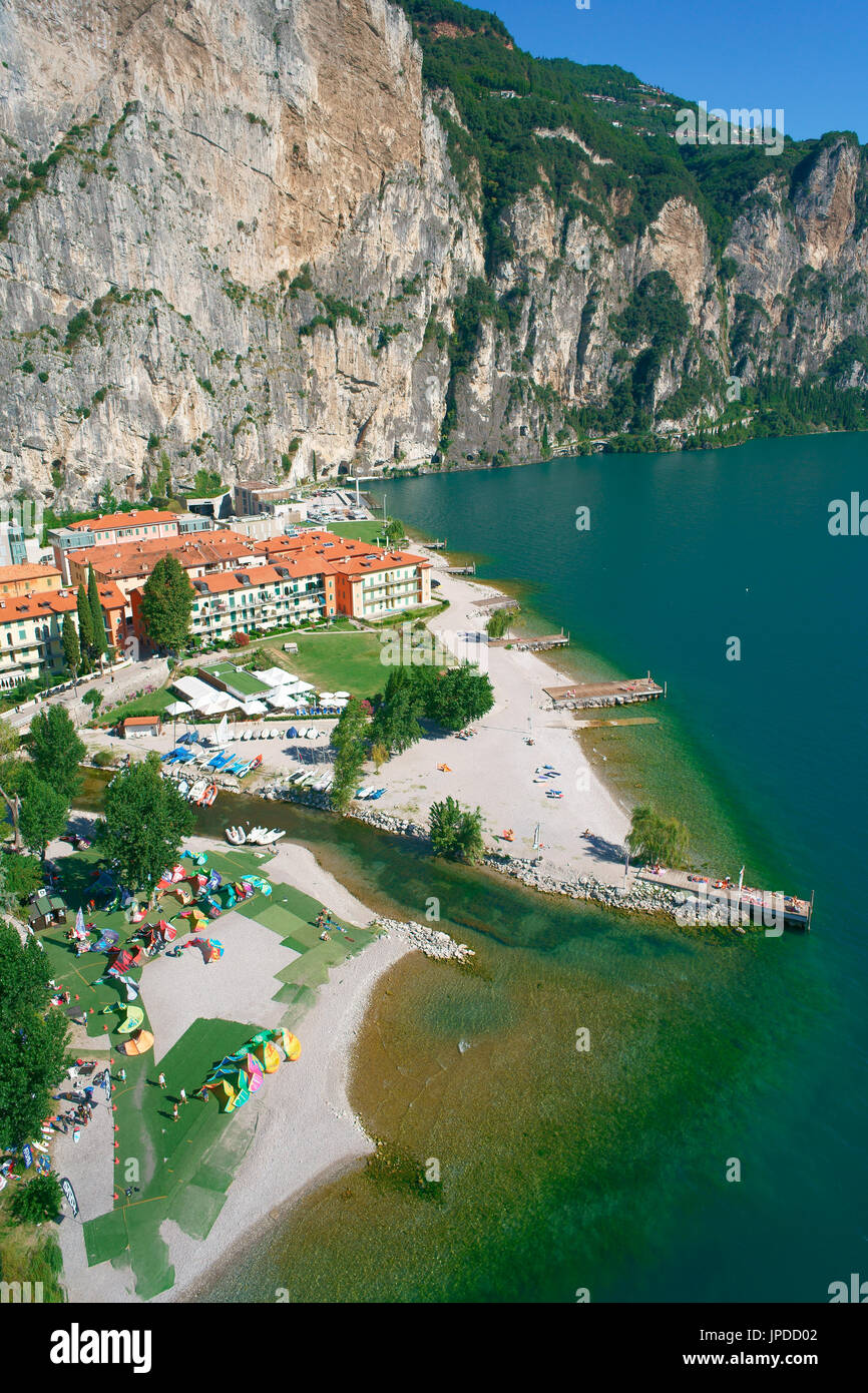 AERIAL VIEW. Kitesurfing kites being prepared for water sports enthusiasts at the idyllic spot of Campione del Garda. Lake Garda, Lombardy, Italy. Stock Photo