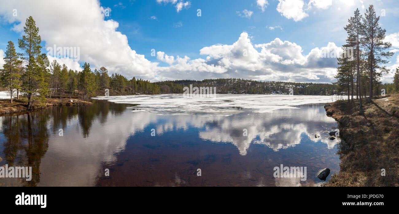 small lake ice forest woods blue sky clouds Norway Northern Europe water reflection reflections background backgrounds Stock Photo