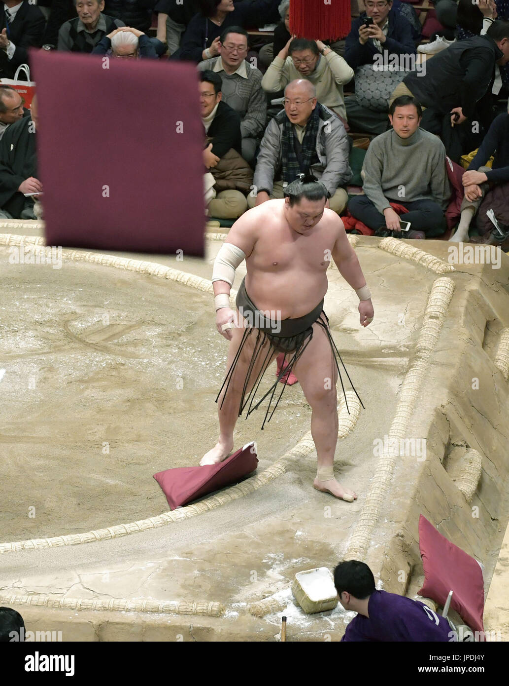 Spectators throw cushions into the ring after yokozuna Hakuho suffered