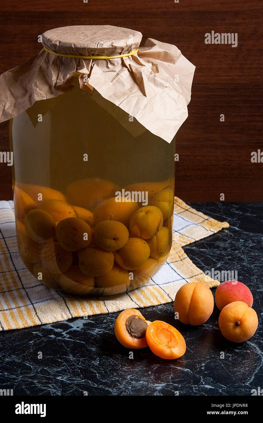 Ripe organic apricots harvested at summer time and big glass jar with