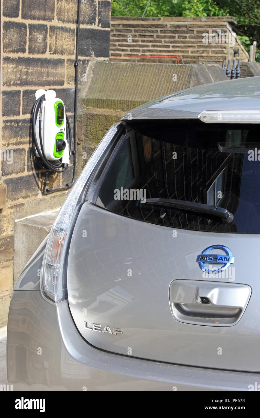 All electric Nissan Leaf car and charging station outside private house. Stock Photo