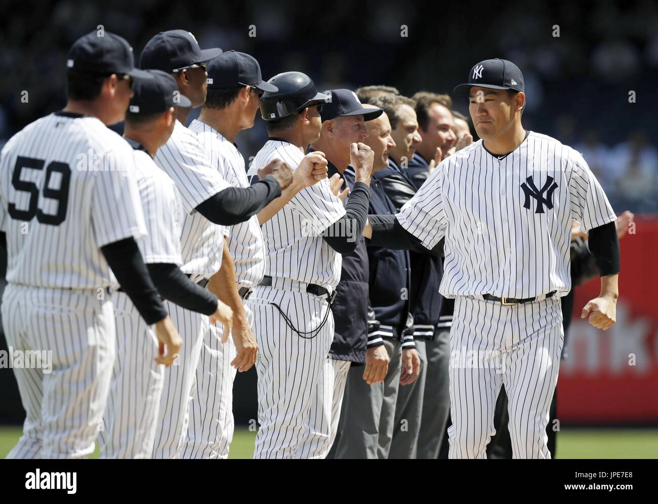 New York Yankees pitcher Masahiro Tanaka (far R) fist bumps teammates