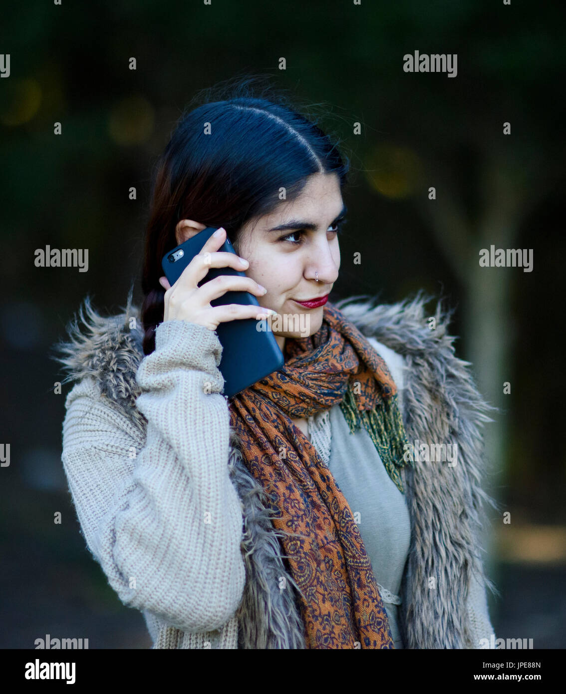 Persian girl talking on her mobile phone outdoors Stock Photo