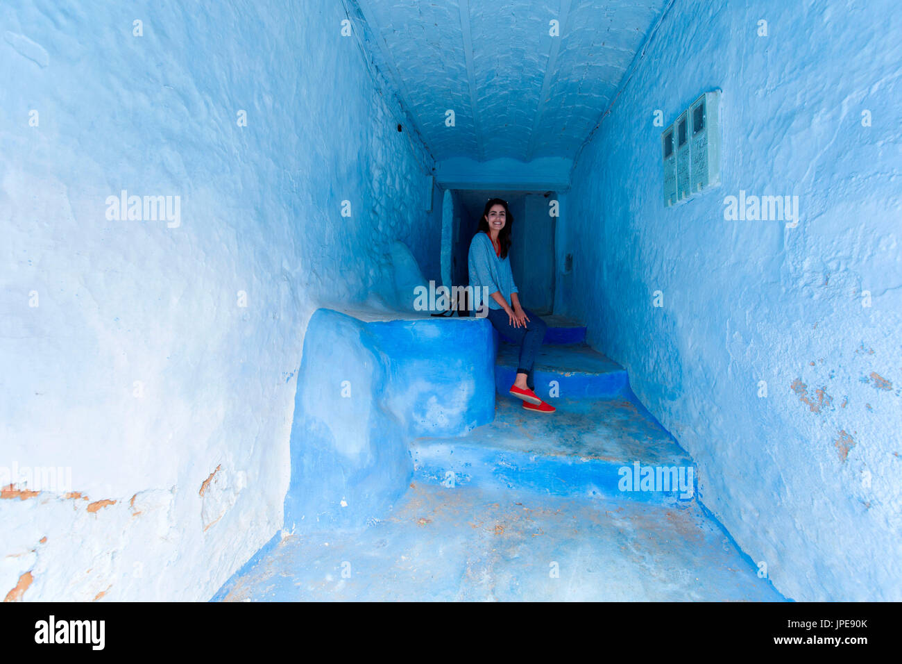 North Africa, Morocco, Chefchaouen district. Moroccan girl sitting at the entrance of a typical house in chefchaouen Stock Photo