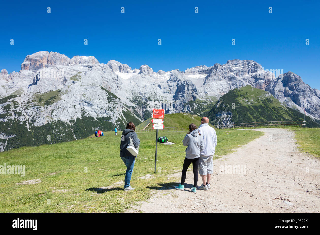 People in the green meadows admire the rocky peaks Doss Del Sabion Pinzolo Brenta Dolomites Trentino Alto Adige Italy Europe Stock Photo