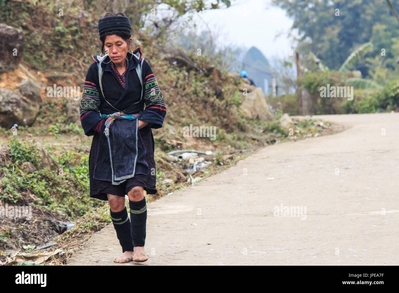Aboriginal woman of the mountains of Sapa, in north Vietnam, dressed with the traditional attire walking to her village Stock Photo