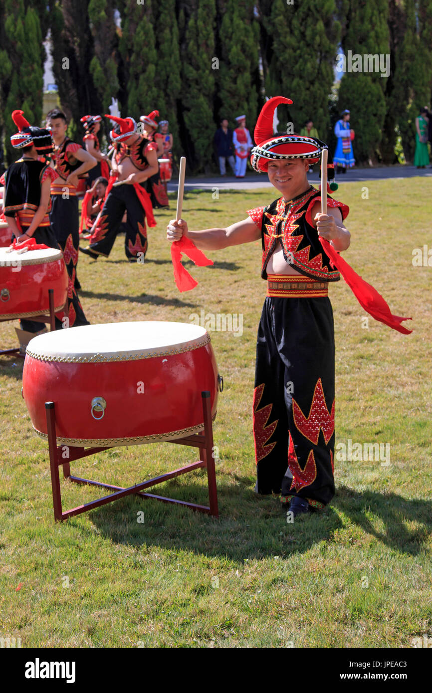 Man playing drums dressed with the traditional attire of Yunnan, in China Stock Photo