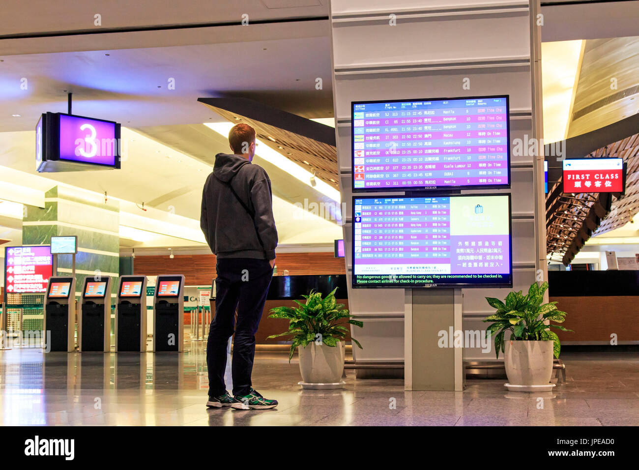 Taipei, Taiwan. Man stading in front of a Flight Information Board inside the Taiwan Taoyuan International Airport, the busiest airport in the country and the main international hub for China Airlines and EVA Air. Stock Photo