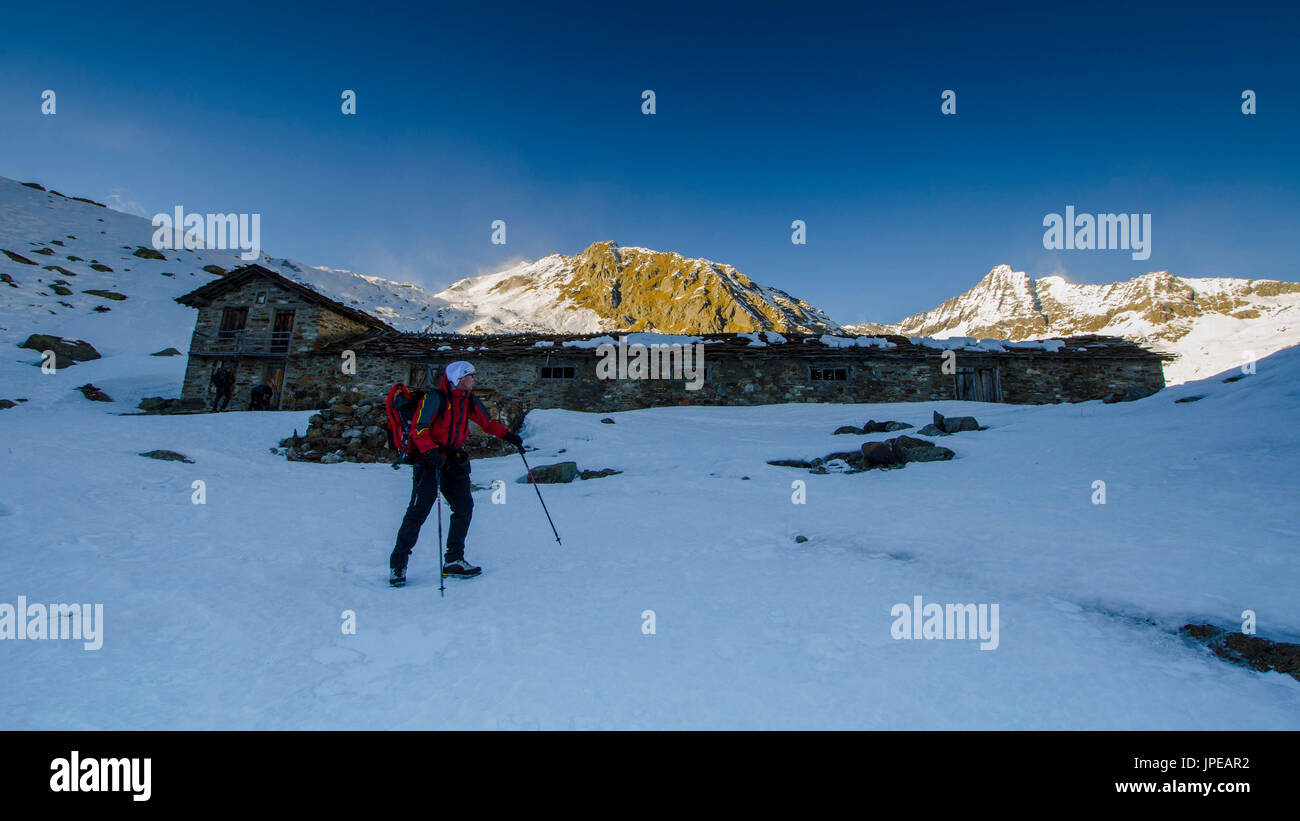 Alpinist in front of a pasture (Soana valley, Gran Paradiso National Park, Piedmont, Italian alps, Italy) Stock Photo