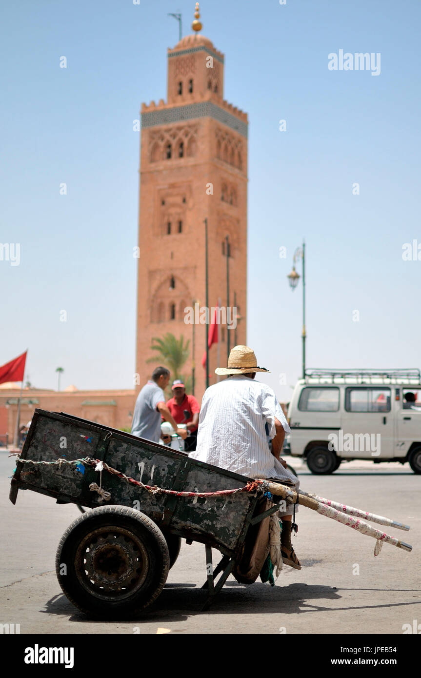 Man on a handcart, infront of Minaret of the Koutoubia, Marrakech, Morocco, North Africa Stock Photo