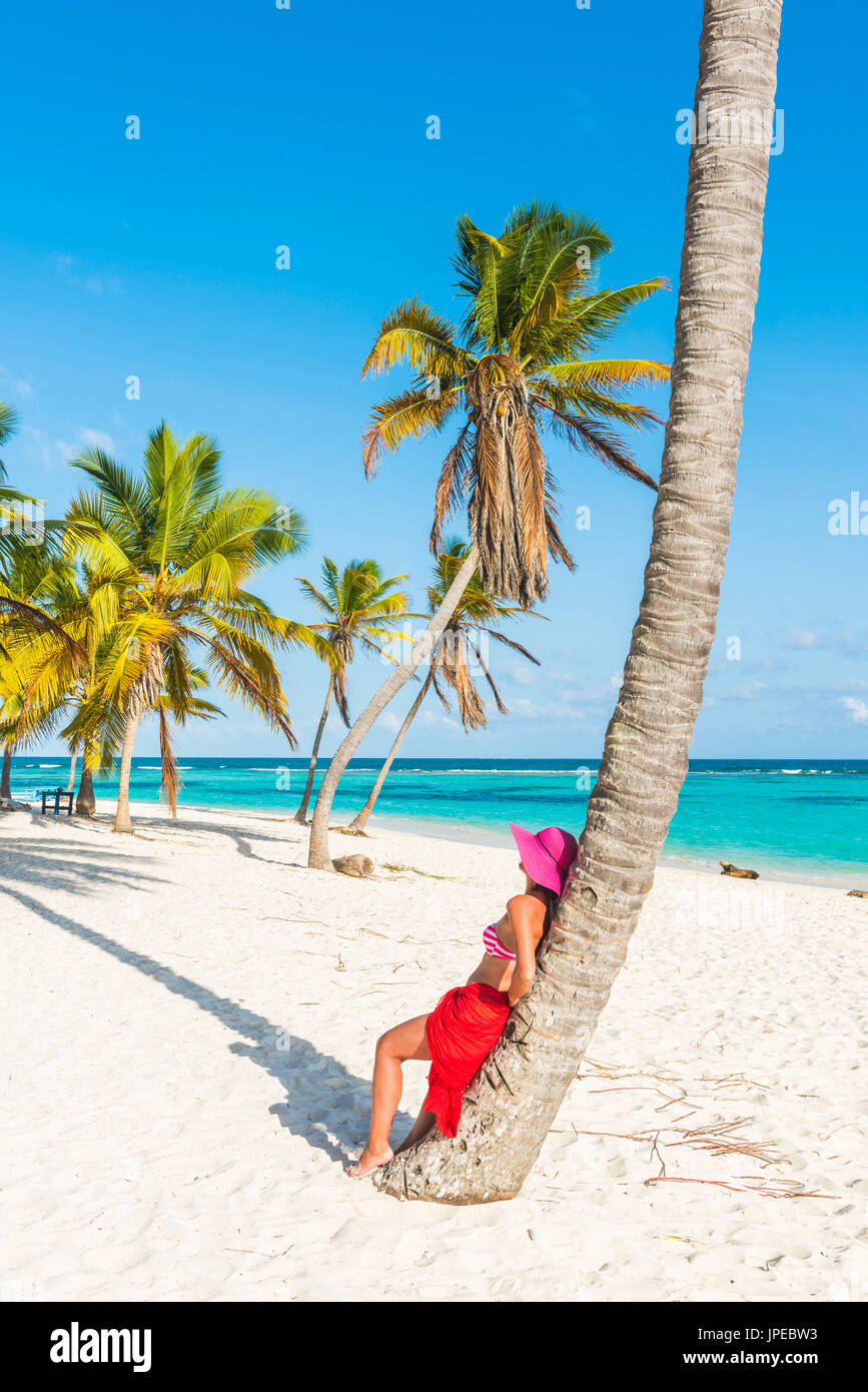 Canto de la Playa, Saona Island, East National Park (Parque Nacional del Este), Dominican Republic, Caribbean Sea. Beautiful woman with red sarong relaxing on the palm-fringed beach (MR). Stock Photo