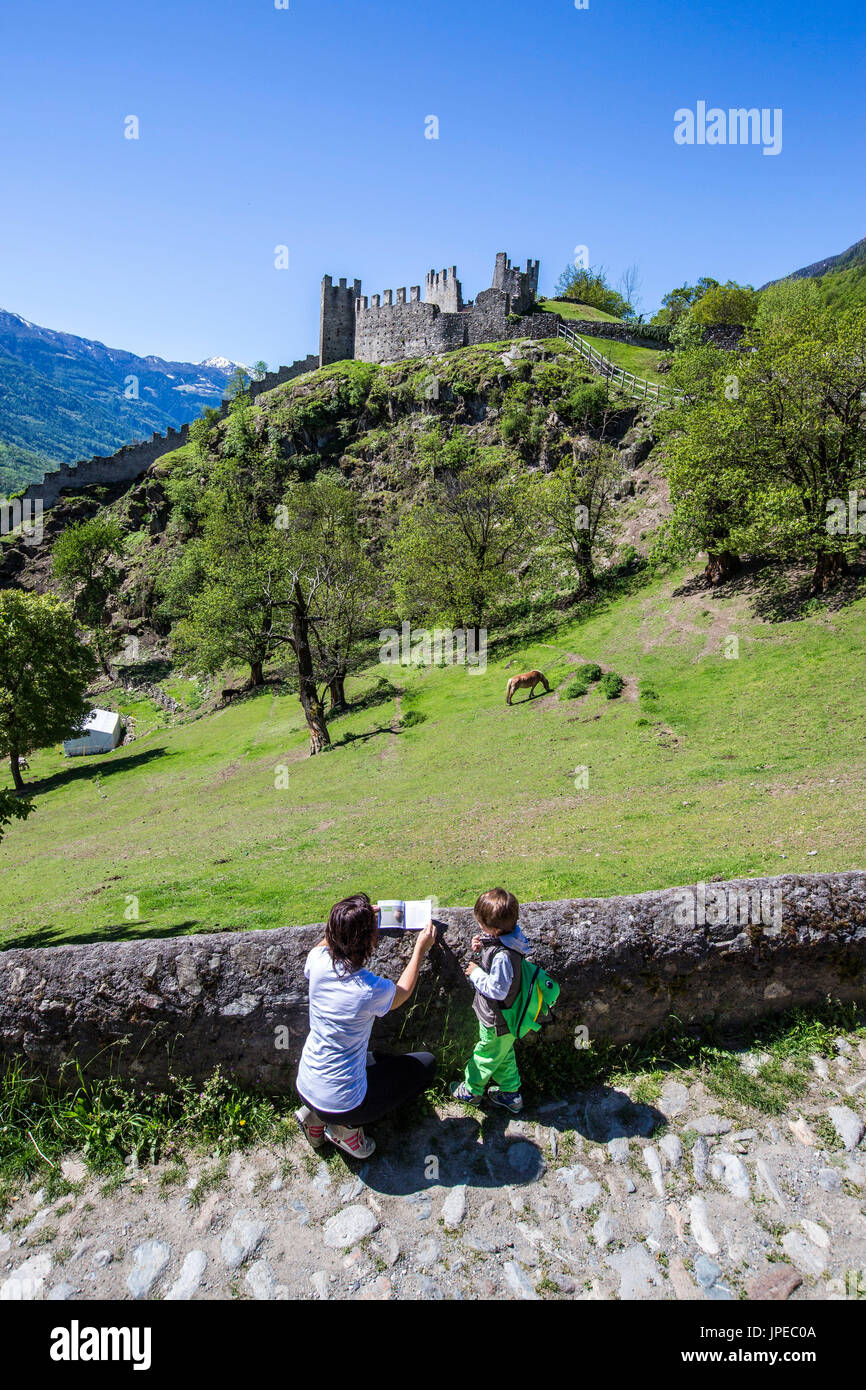 Tourists consult the hiking map in the vicinity of Castle Visconti Venosta in Grosio. Province of Sondrio. Valtellina. Lombardy. Italy. Europe Stock Photo