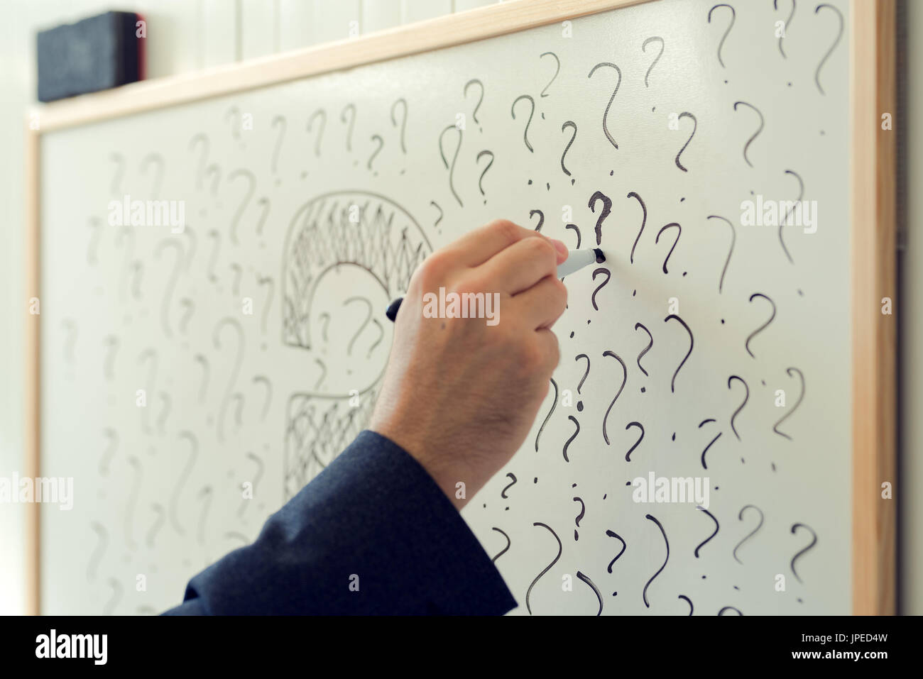Businessman sketching many question marks on office whiteboard, uncertainty and unpredictability in business Stock Photo