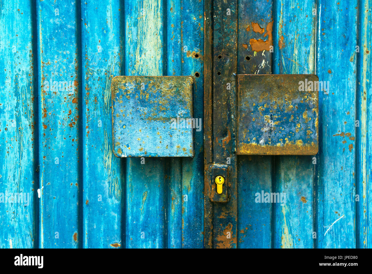 Grunge blue metal garage door, weather worn metallic entrance to a private enclosed parking space Stock Photo