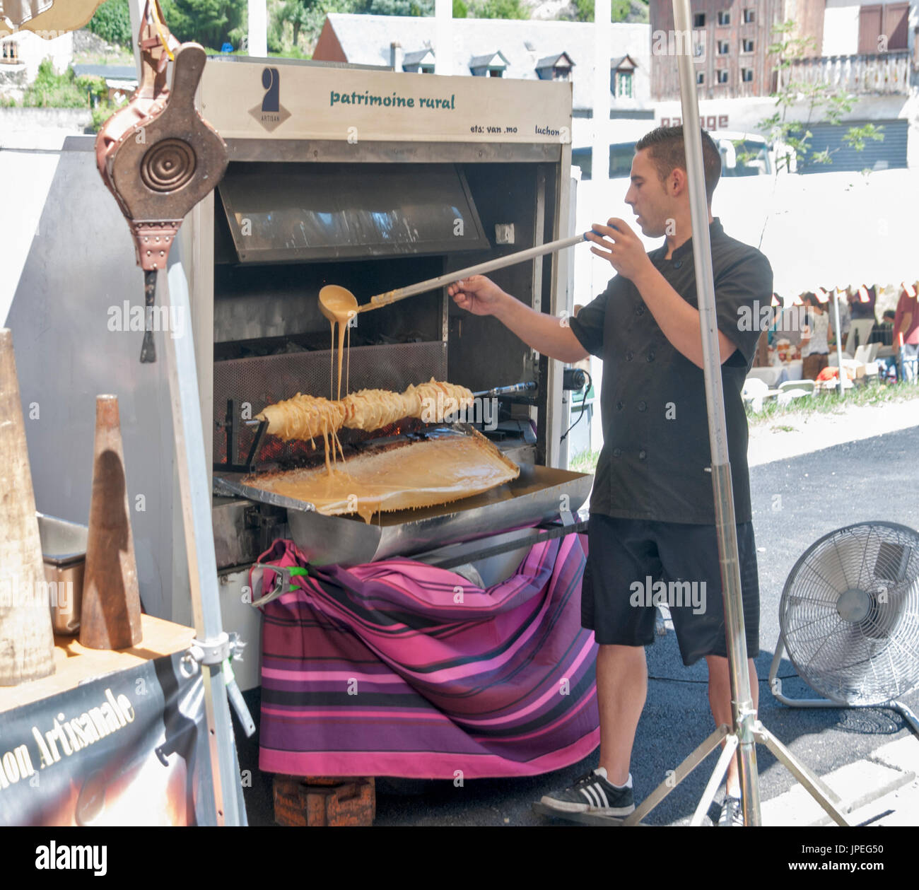 Cooking A Cake On A Spit Over A Wood Fire Sunday Market At Arreau Hautes Pyrenees France Stock Photo Alamy