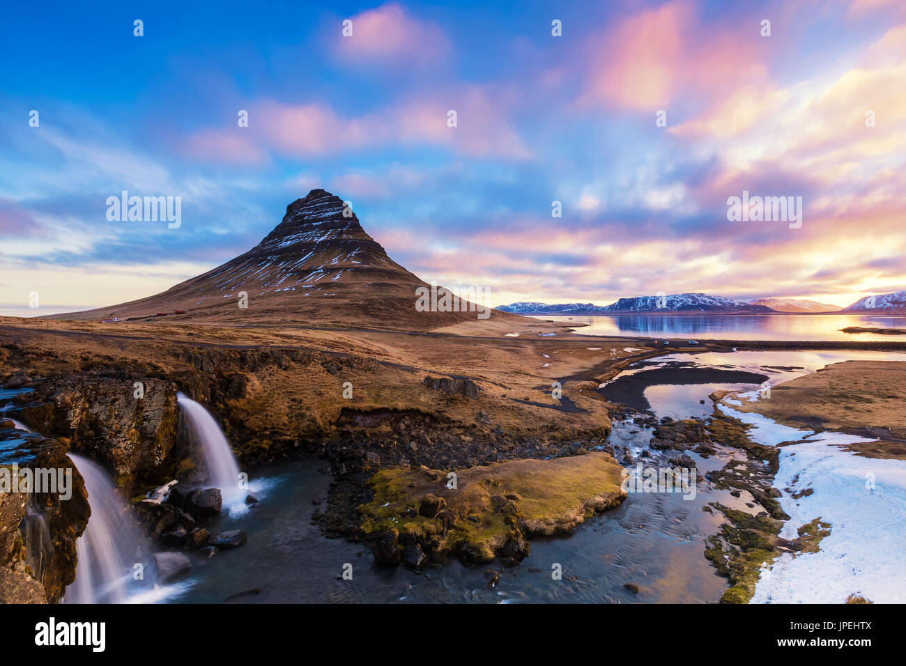 Spring sunrise over the famous Kirkjufellsfoss Waterfall with Kirkjufell mountain in the background in Iceland Stock Photo