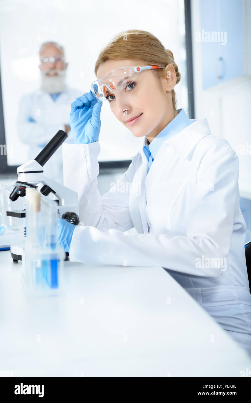 Attractive middle aged scientist working with microscope in chemical lab Stock Photo