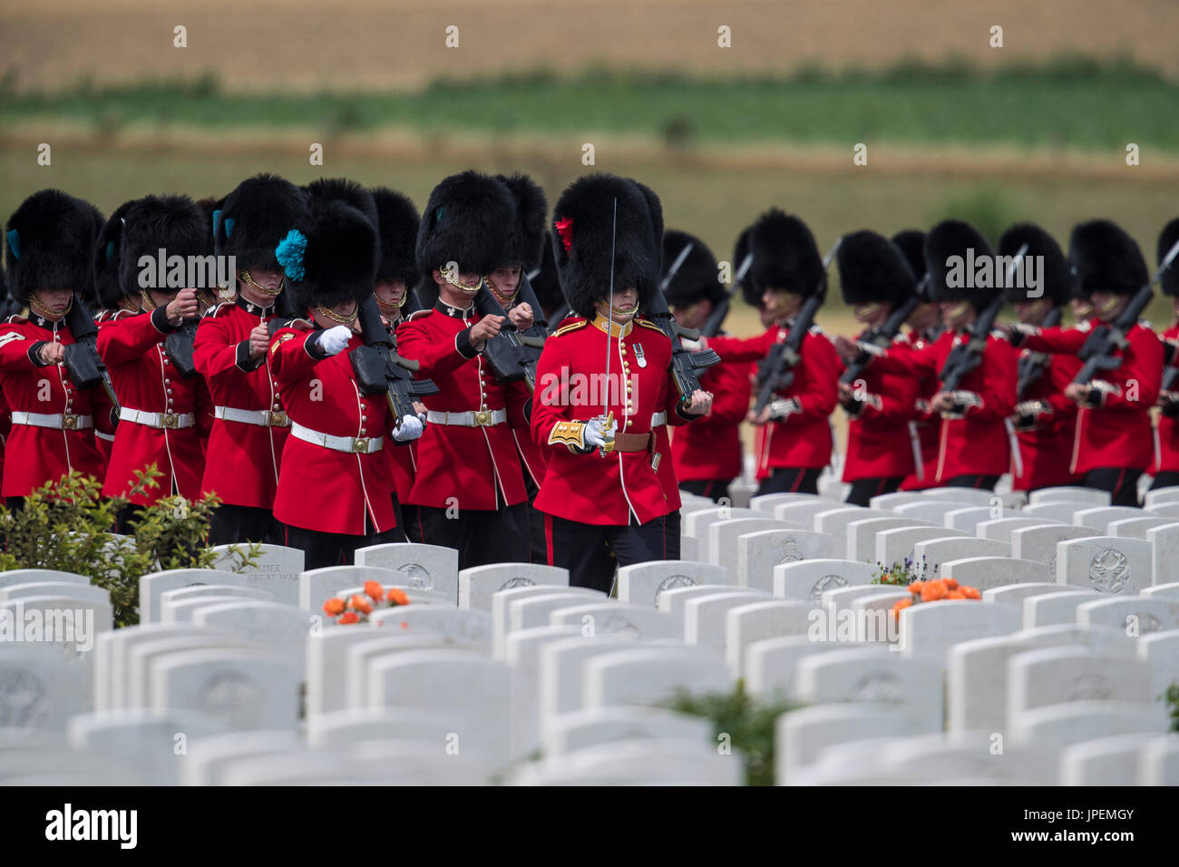 British Troops take part in the commemoration events for the World War One Battle of Passchendaele at the Tyne Cot Cemetery near Ypres in Belgium. The 1st Battalion of the Irish Guards march through the grave stones Stock Photo