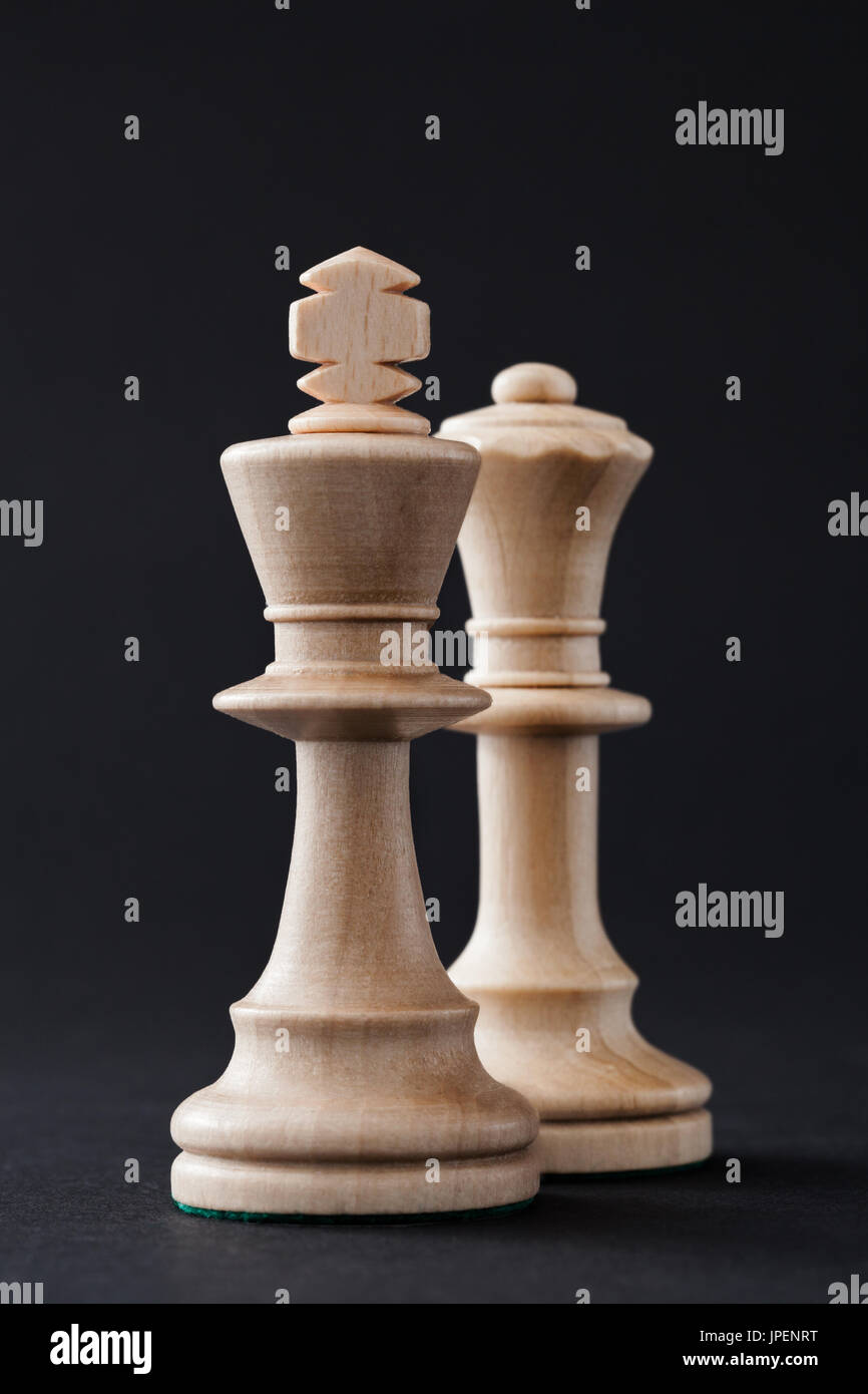 Wooden chess pieces, figures white king and queen isolated on black colored background. Stock Photo