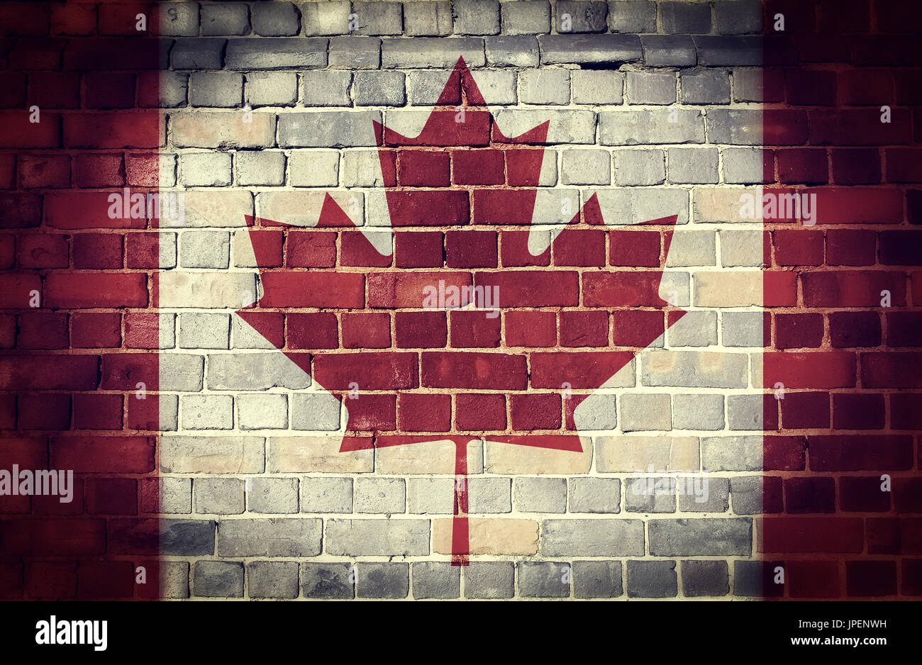 Faded Canadian flag on an old brick wall background with a dark vignette Stock Photo