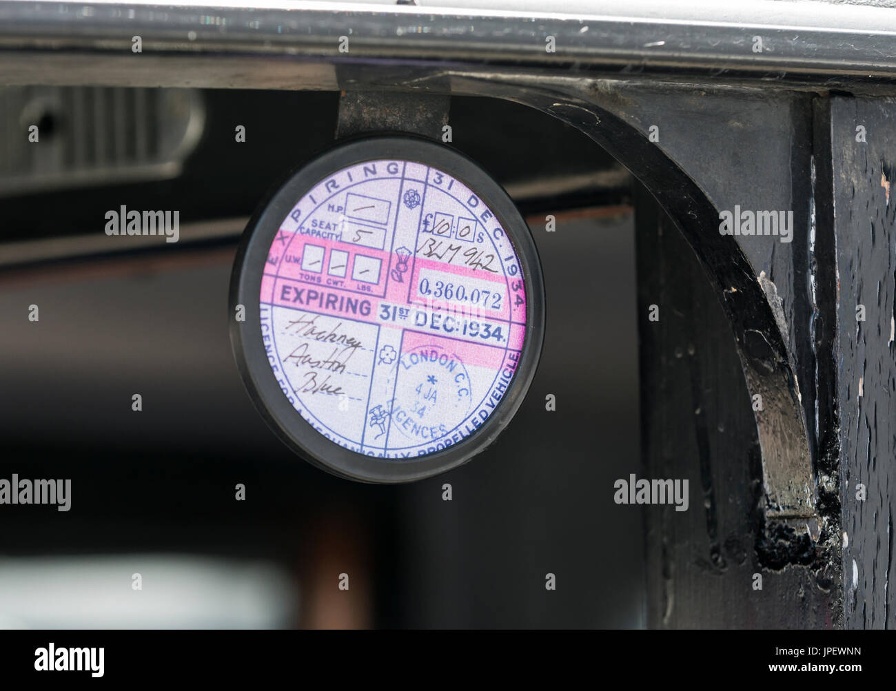 Expired 1930s road tax disc fitted to a vintage Austin 12/4 London taxicab in the UK. Stock Photo