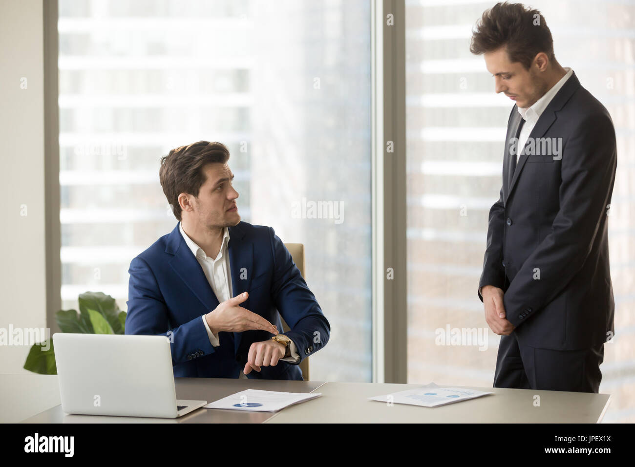 Subordinate receiving reprimand from boss for being late, missin Stock Photo