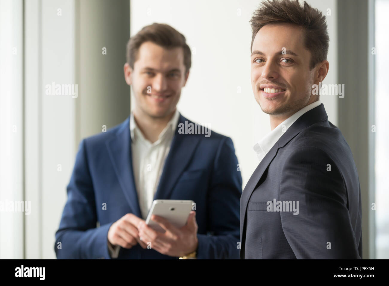 Smiling young businessman looking at camera, application develop Stock Photo