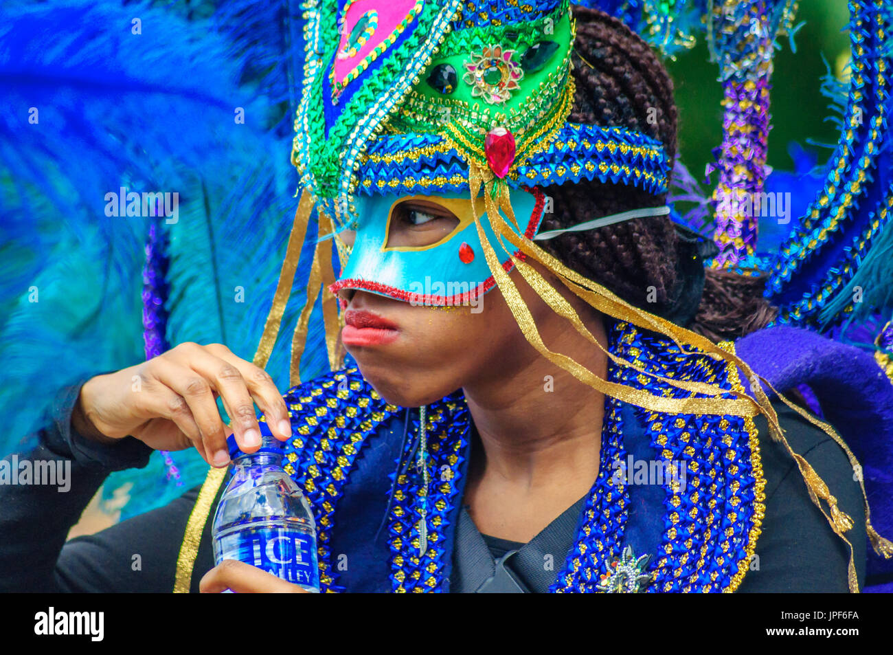 Female performer wearing a colorful costume, headdress and mask on the