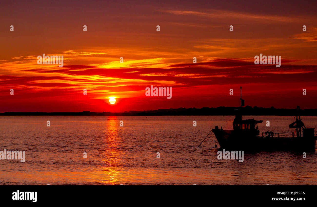 Glorious Sunset over the River Stour at Mudeford Quay , Dorset , with boats  in silhouette on a beautiful Autumn evening Stock Photo