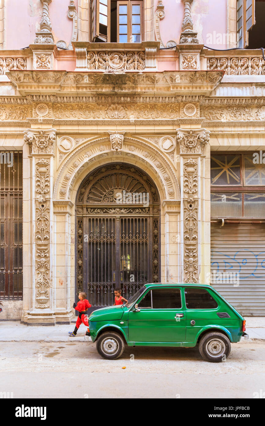 Old Fiat Cinquecento parked in front of historic building in street scene with playing children, Havana, Habana Vieja, Cuba Stock Photo