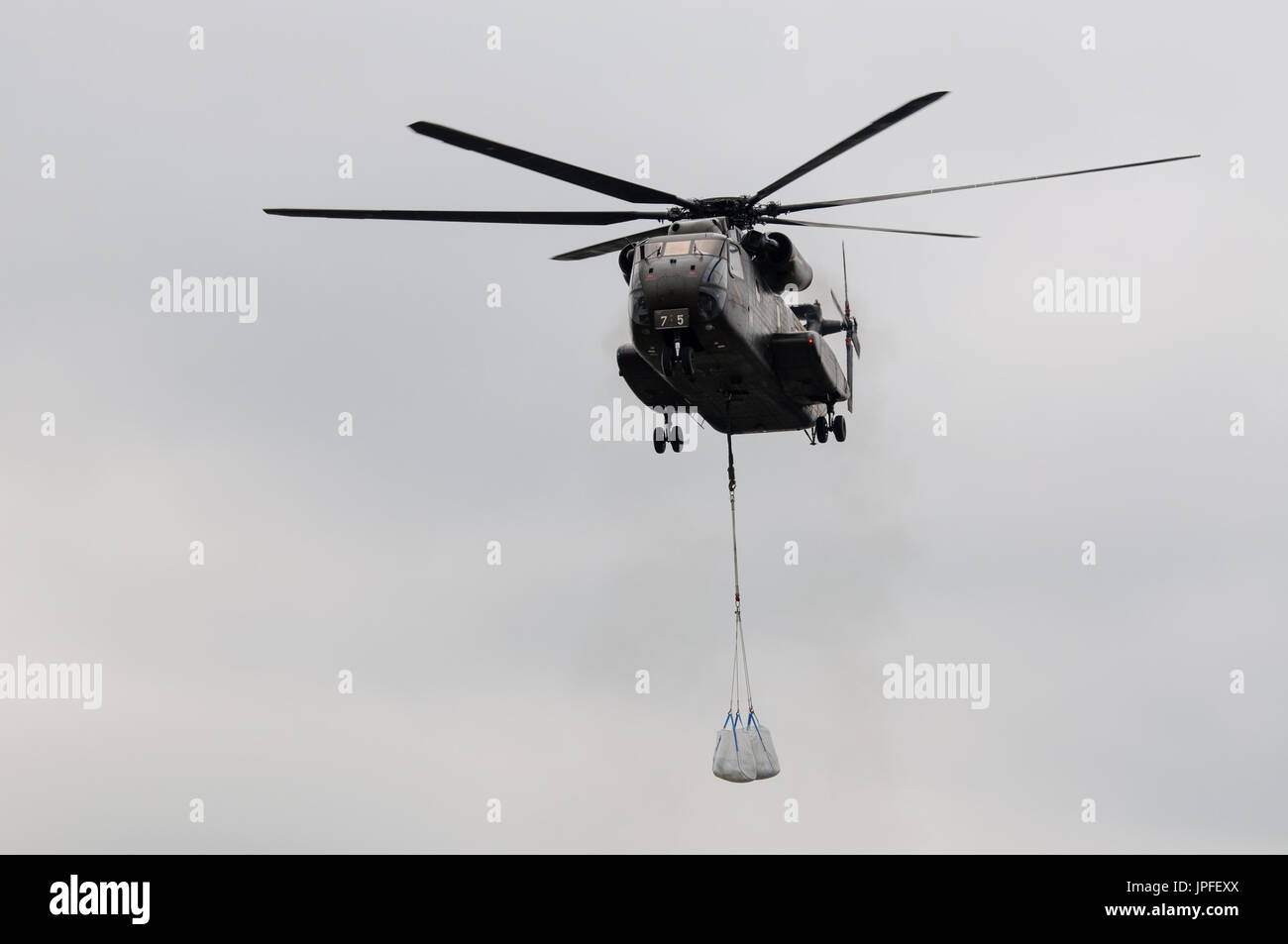 military helicopter about to transport sand bags to secure a dike against the flood Stock Photo