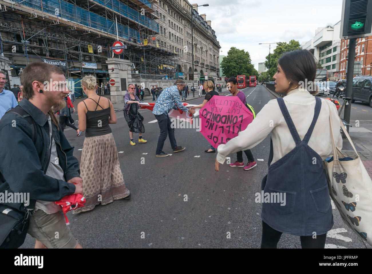 London, UK. 1st August 2017. Rising Up environmental protesters walk onto the busy Marylebone Road at Baker St for their 'Staying Alive' road-block disco protest to raise awareness and call for urgent action over the high pollution levels from traffic on London streets which cause 10,000 premature deaths each year. They walked into the road with banners and umbrellas with the message Stop Killing Londoners and sat down while a statement was read explaining why they were protesting and that it would only be a delay of 5-10 minutes, then danced in front of the blocked traffic before leaving the  Stock Photo