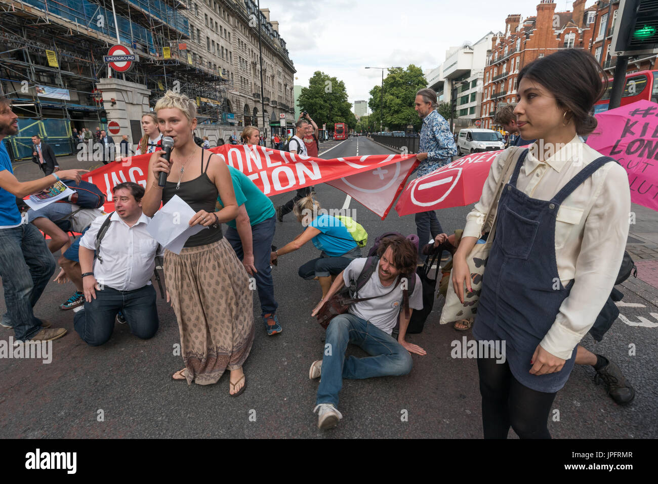 London, UK. 1st August 2017. Rising Up environmental protesters blocking the busy Marylebone Road at Baker St read out a statement explaining their 'Staying Alive' road-block disco protest to raise awareness and call for urgent action over the high pollution levels from traffic on London streets which cause 10,000 premature deaths each year. They walked into the road with banners and umbrellas with the message Stop Killing Londoners and sat down while the statement was read explaining why they were protesting and that it would only be a delay of 5-10 minutes, then danced in front of the blocke Stock Photo
