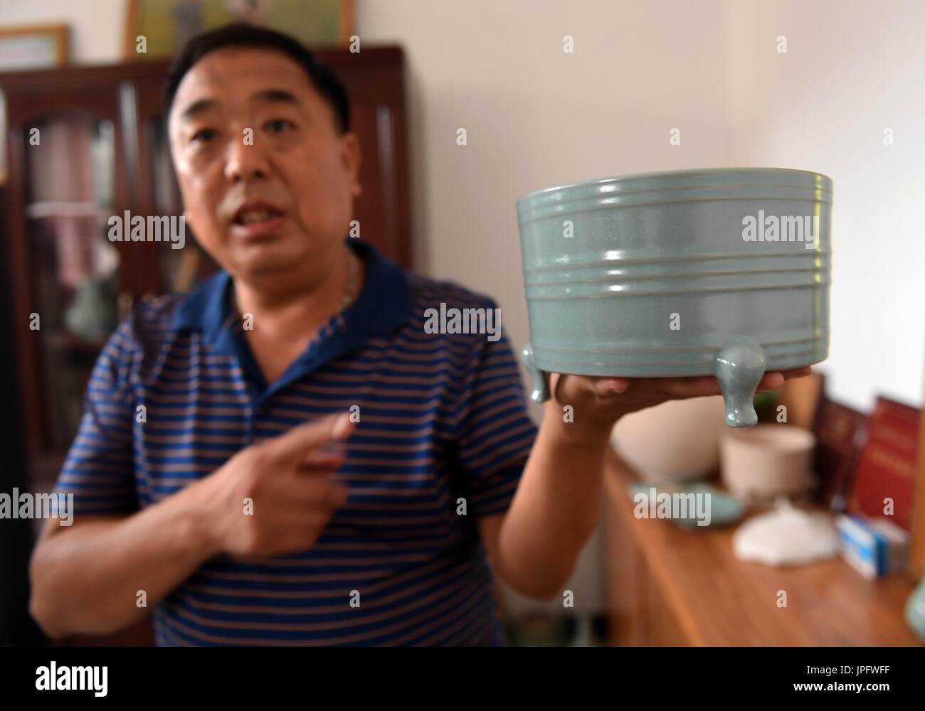 (170802) -- ZHENGZHOU, Aug. 2, 2017 (Xinhua) -- A staff member displays a Ru porcelain at a Ru porcelain manufacture at Baofeng County, central China's Henan Province, Aug. 1, 2017. Baofeng county was famous for producing Ru porcelain in China's ancient times. To boost economy, local authority keeps making efforts to revive production of Ru porcelains in recent years. Up to now, over 60 manufactures produce more than 200,000 pieces per year. Ru porcelain was named after one of five famous kilns producing the most beautiful and distinctive porcelains in Song Dynasty (960-1279). The five famous Stock Photo