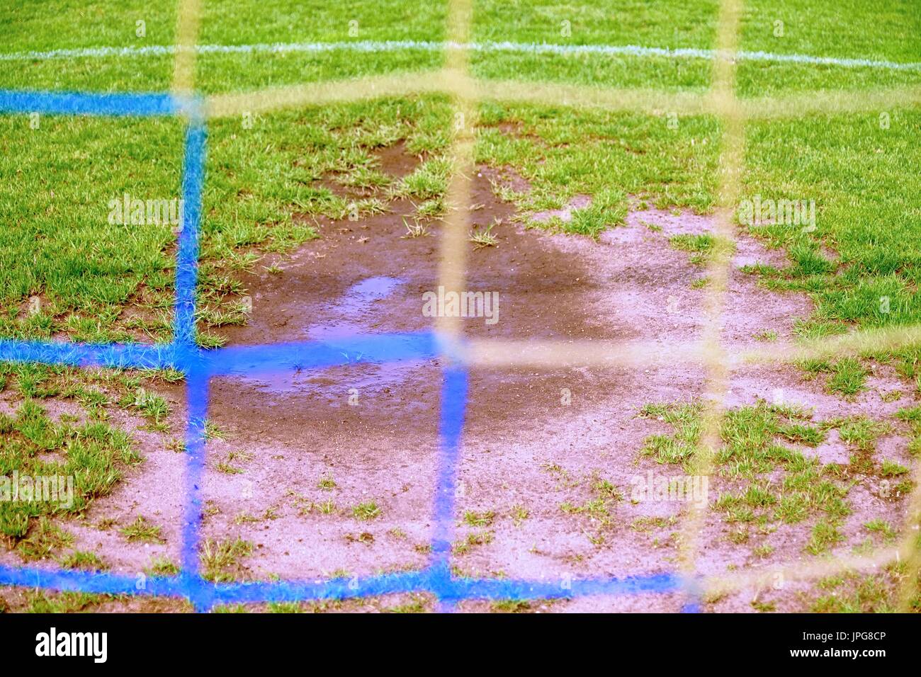 View through football gate to water and mude in poor soccer field