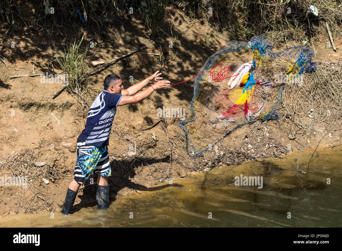 A young man fishing with a net in a lake. Colombia, South America. Stock Photo