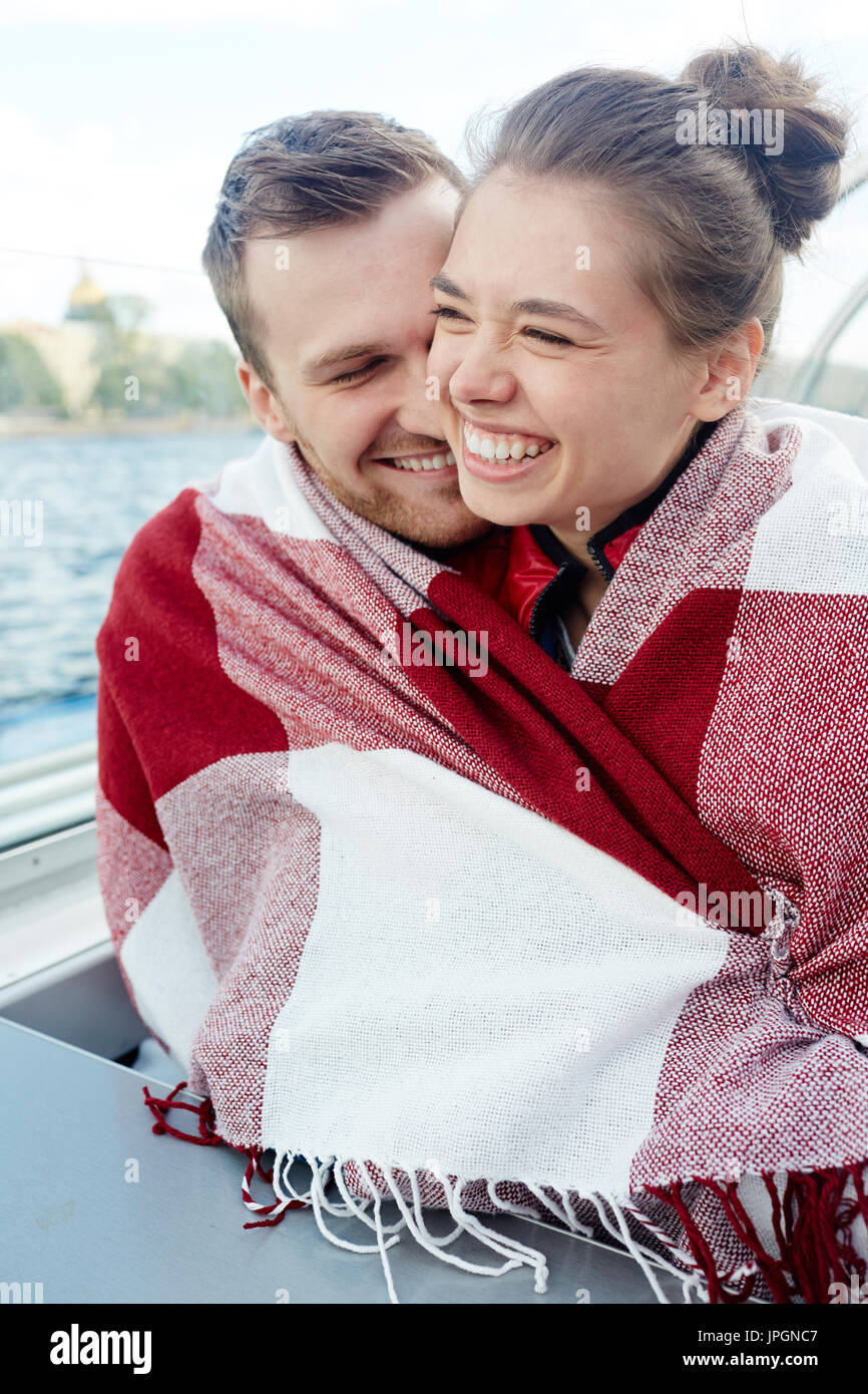 Joyful couple in embrace wrapped in plaid Stock Photo