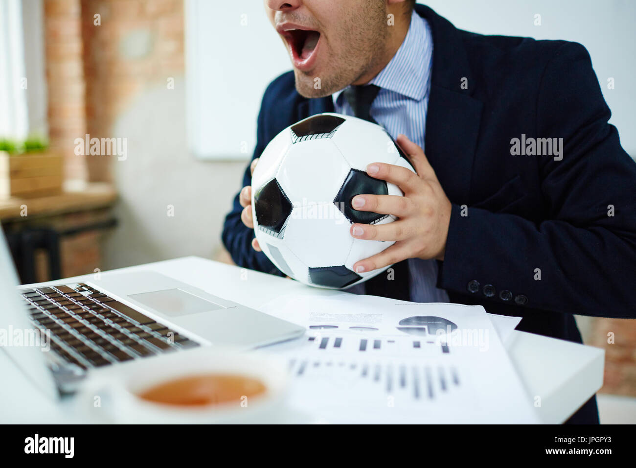 Businessman watching online football match broadcast in office Stock Photo