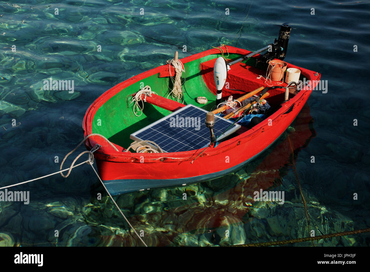 tiny brightly coloured fishing boat, solar powered, in the harbour